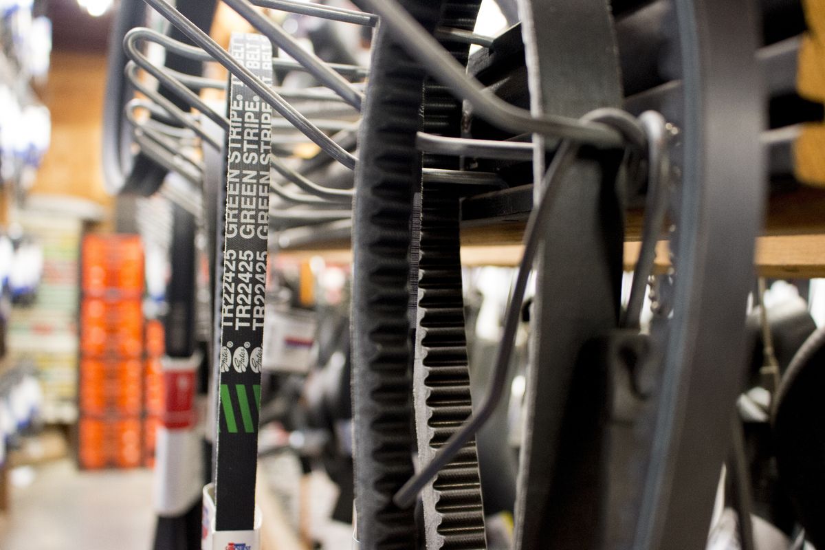 Automotive drive belts and timing belts displayed on metal racks in a parts warehouse